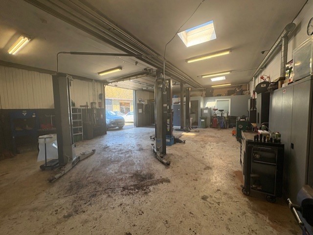 Værkstedshal med lifte, værktøjsvogne og en åben port